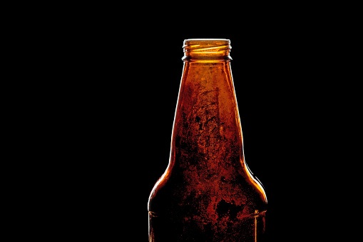 Close-up photograph of a single vintage beer bottle against a black background with copy space.