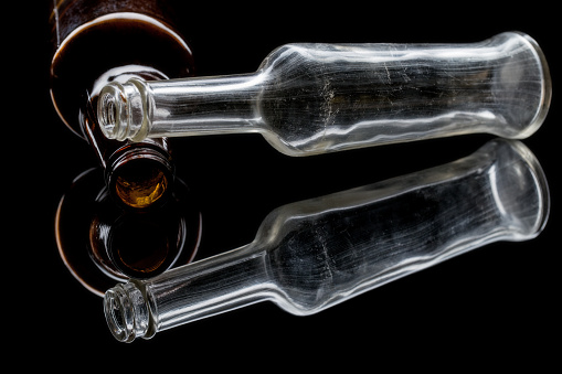 Vintage beer and soda pop bottles on a reflective black background.