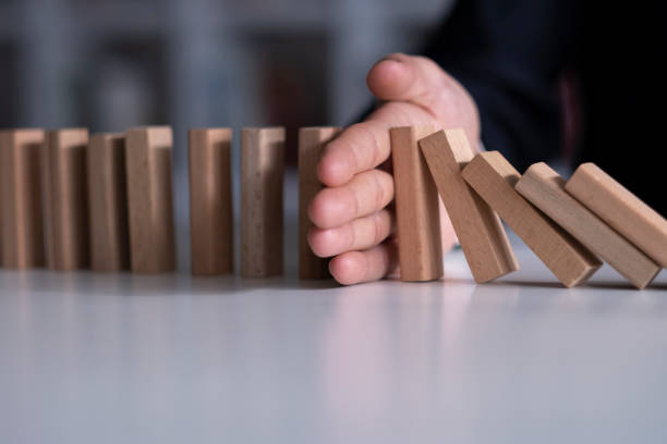 Businessman Stop Domino Effect. Risk Management and Insurance Concept Businessman Stop Domino Effect. Risk Management and Insurance Concept Risk Management stock pictures, royalty-free photos & images