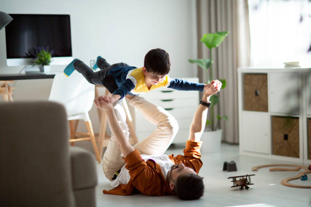 Joyful young man father lifting excited happy little son.