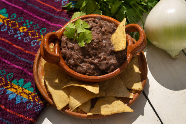 mexikanische gebratene bohnen mit totopos auf weißem hintergrund - frijoles stock-fotos und bilder