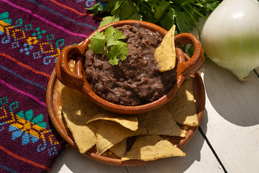 Traditional mexican refried beans with totopos on white background
