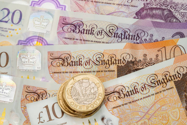 великобритания один фунт монеты размещены на фоне британских банкнот - one pound coin british currency coin paper currency стоковые фото и изображения