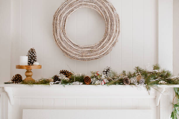 istock Modern rustic fire place winter decoration. Christmas Scandinavian house decor - white wreath, pine cones and christmas tree branches. 1292005163