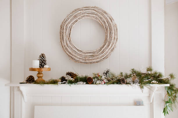 istock Modern rustic fire place winter decoration. Christmas Scandinavian house decor - white wreath, pine cones and christmas tree branches. 1292005676