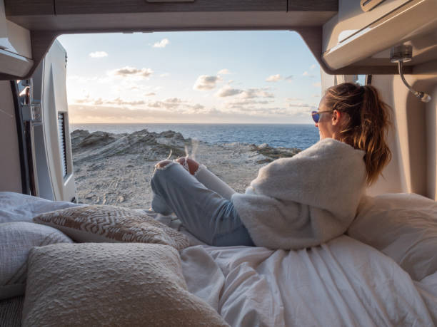 donna sdraiata sul retro di un furgone che guarda l'oceano - car rear view behind car trunk foto e immagini stock