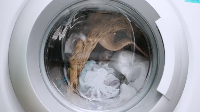 Close up view porthole of washing machine. Washing clothes process in slow motion
