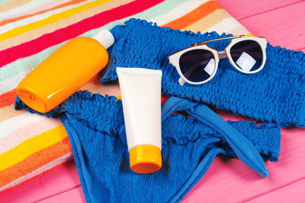 istock Blue bikini with sunblock cream bottle on bright pink wooden background 1292021171