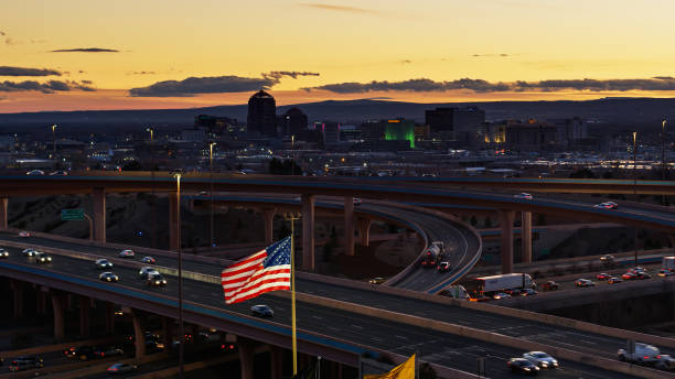 drapeau américain volant devant l’échangeur d’autoroute et la ligne d’horizon d’albuquerque - projectile de drone - aerial view albuquerque new mexico usa photos et images de collection