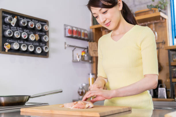 asian woman cooks in a kitchen,chicken - white meat flash imagens e fotografias de stock