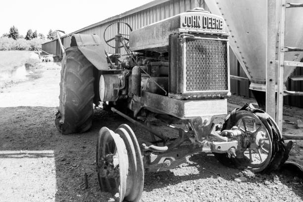 : A black and white photograph of a vintage tractor working in vast, undulating fields, capturing the essence of rural life.