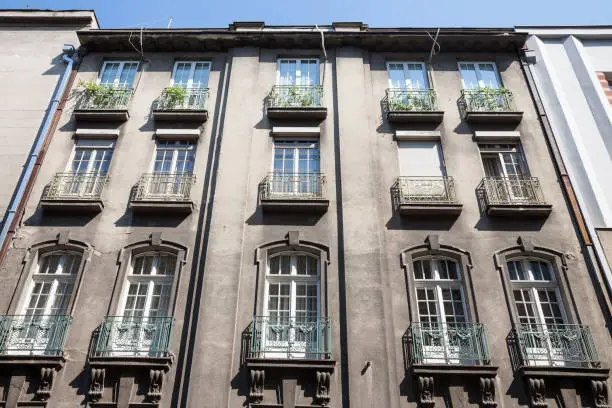 Photo of Typical facade of an Old residential building in Vracar district with a grey polluted wall in the city center of Belgrade, the capital city of Serbia, during a sunny afternoon.