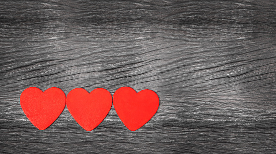 three hearts on the wooden background. red hearts on gray old wood