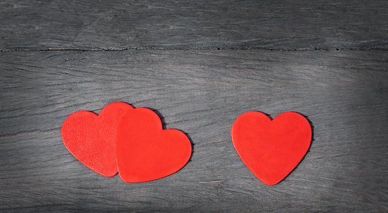 three hearts on a wooden background. red hearts on gray old wood. couple hearts and one heart