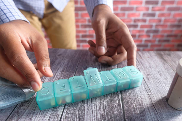 istock man's hands taking medicine from a pill box 1292031613