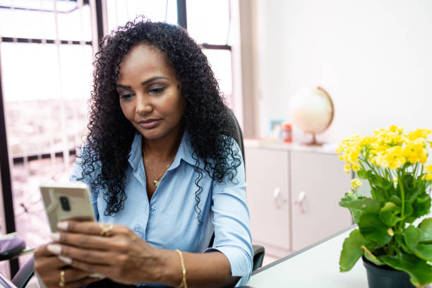istock Elegant black woman using portable device on her cell phone. 1292032385