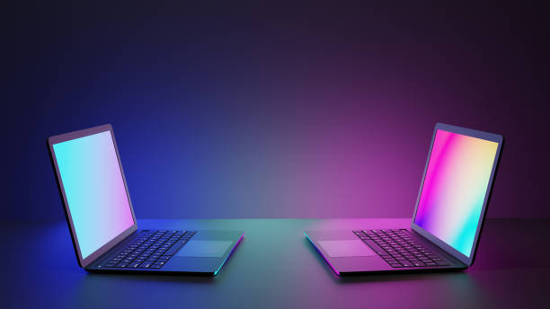 istock Two colorful laptop computers on desk with pink blue lighting dark background. 3D Rendering image. 1292038833