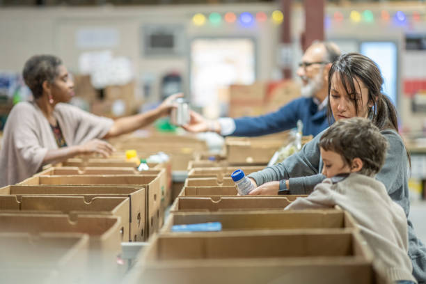 Volunteers at a Food Bank Small group of people donating their time by working in a warehouse to organize and distribute non-perishable goods to families and people in need. giving tuesday stock pictures, royalty-free photos & images