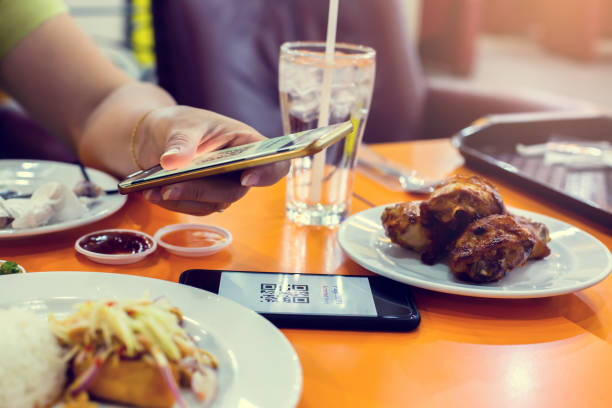 istock Selective focus to smartphone in hand to scan QR code on tag with blurry food, dessert and customers in restaurant to accepted generate digital pay without money. 1292040273