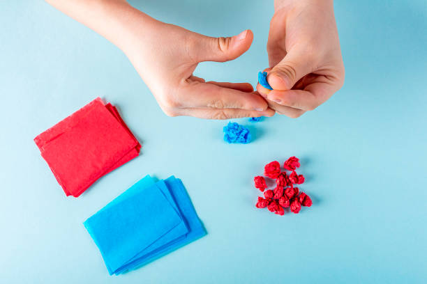 istock Concept of DIY and kid's creativity. Step by step instruction: make  heart. Step2 Child's hands crumples pieces of colored paper. Valentine's Day craft. Fine motor skills 1292041022