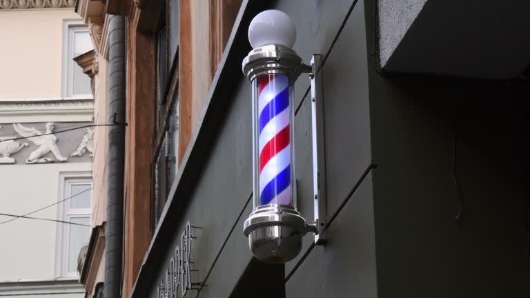 Striped barber pole rotating on wall of hairdresser shop in old building