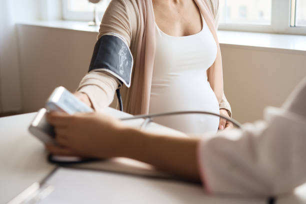 Doctor measuring blood pressure of her pregnant patient stock photo