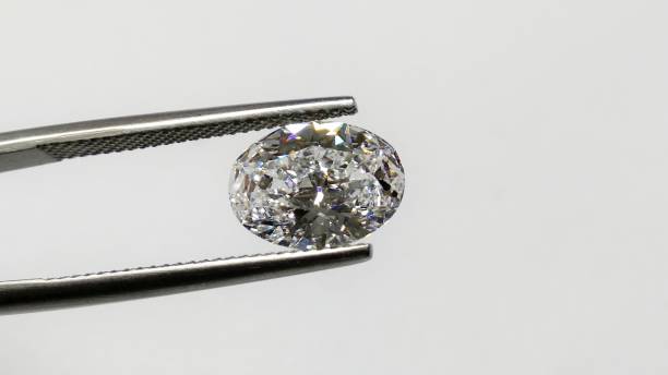istock Oval shaped polished solitaire diamond held by tweezers in white background 1292054588