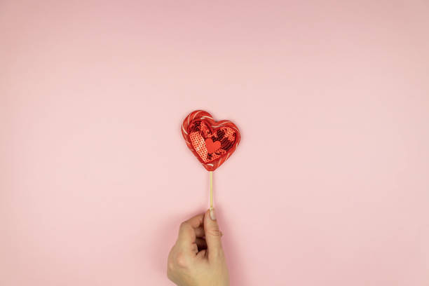 istock Female hands holding red sequin heart on pink background. Creative minimal layout with copy space 1292057115