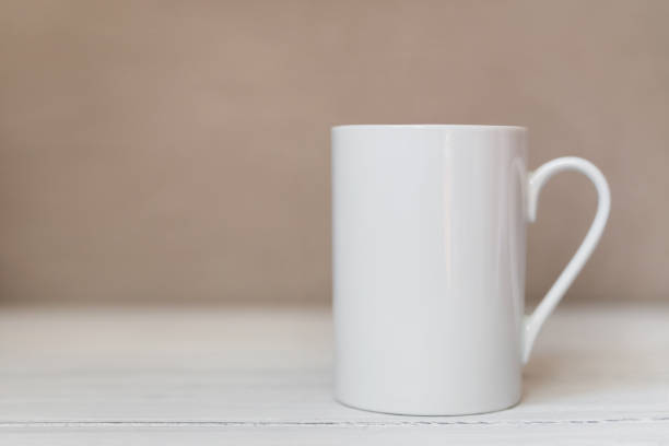 istock White cup, mug on white wooden background. Cofee or tea mockup 1292057965