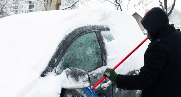 istock Man scraping the snow of a car using the brush. 1292068635