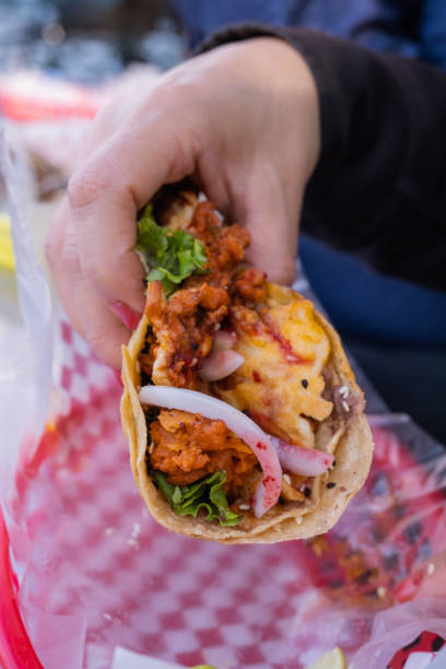 istock Female hand holding a vegetarian taco above a plastic basket 1292068795