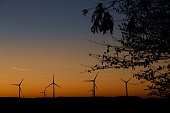 Closeup pf wind turbines over the hill during a beautiful dusk.