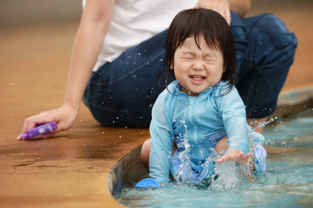 Two children playing and splashing water in a natural river surrounded by green trees on a warm summer day