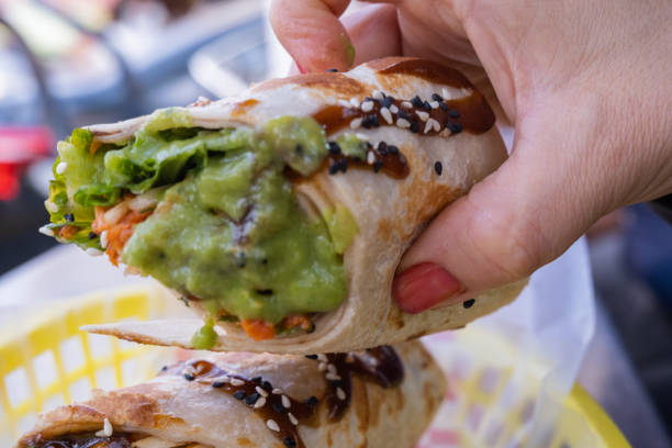 istock Female hand holding a burrito covered with guacamole 1292069637