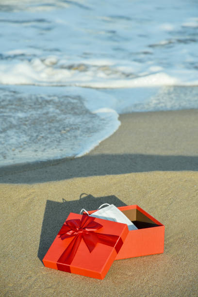 istock Protective face mask in a gift box on the sandy beach 1292069686