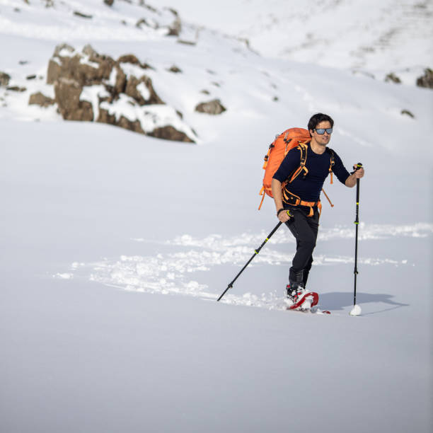 istock Young man walking with snowshoes uphill in high mountains 1292074546