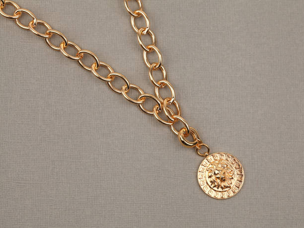 istock Golden pendant with chain on beige textured background 1292076520