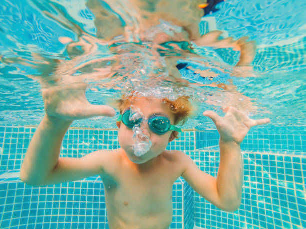 istock Underwater Young Boy Fun in the Swimming Pool with Goggles. Summer Vacation Fun 1292084121