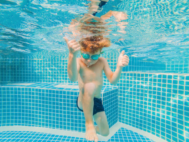 istock Underwater Young Boy Fun in the Swimming Pool with Goggles. Summer Vacation Fun 1292084130