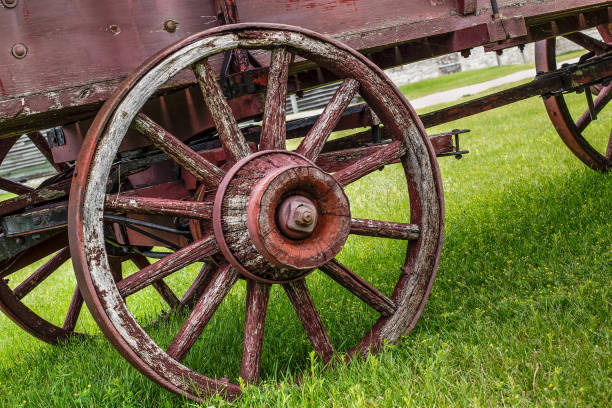 Wild West Style Background With Wagon Wheel Rustic wooden covered wagon in faded red barn paint in horizontal orientation. rusty old wagon detail stock pictures, royalty-free photos & images