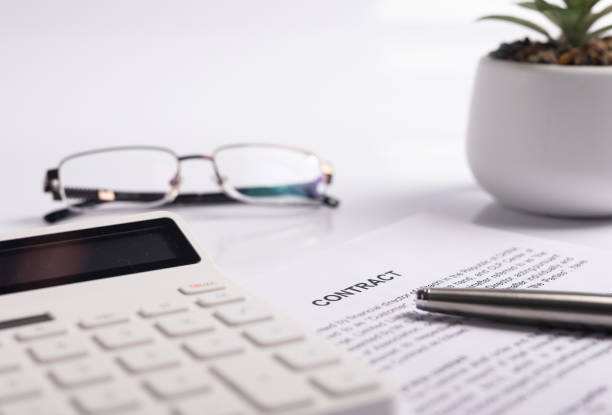 istock Office desk or table with contract paper, documents, calculator, potted plant, pen and eyeglasses. Close up 1292087922