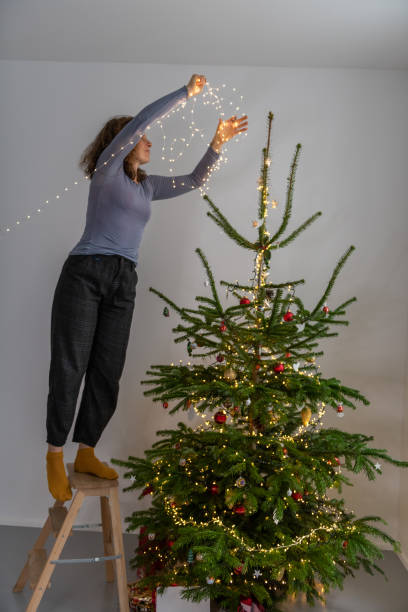 istock Cute curly woman decorating Christmas Tree at Home 1292088163