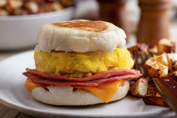 Breakfast Sandwich on an English Muffin Closeup of a breakfast sandwich with egg, ham and cheese on an english muffin english muffin stock pictures, royalty-free photos & images