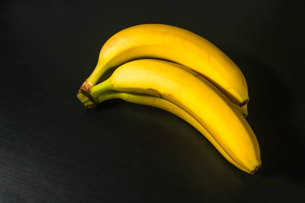 istock Top view of ripe yellow bananas on black background 1292093220
