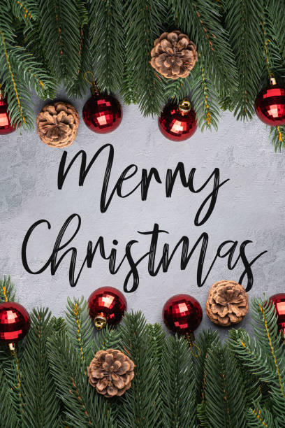 istock Merry Christmas text holidays composition. Red ornament and bauble decorations, fir-tree and pine cones. 1292097769