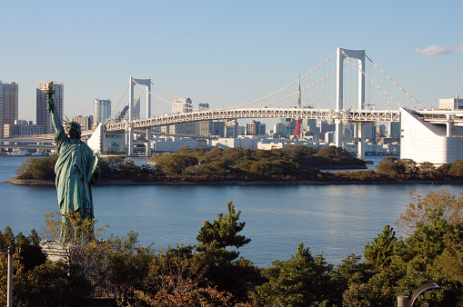 Tokyo city with the replica of the Statue of Liberty and The Rainbow bridge in Odaiba, a large artificial island in Tokyo Bay, Japan.