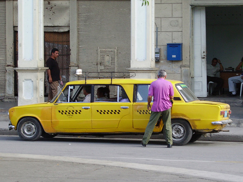 People getting on a old fashioned limousine taxi in Holguin, Cuba