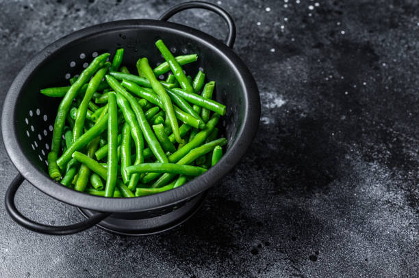 istock Raw green beans in a colander. Black background. top view. Copy space 1292100043