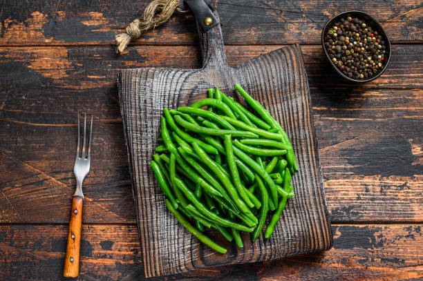 istock Fresh green beans on a cutting board. Dark wooden background. top view 1292101385
