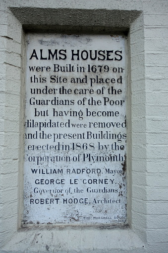 Plymouth England December 2020. Plaque inserted into a wall of Alms houses detailing the history of the houses that were built for the poor of the city.